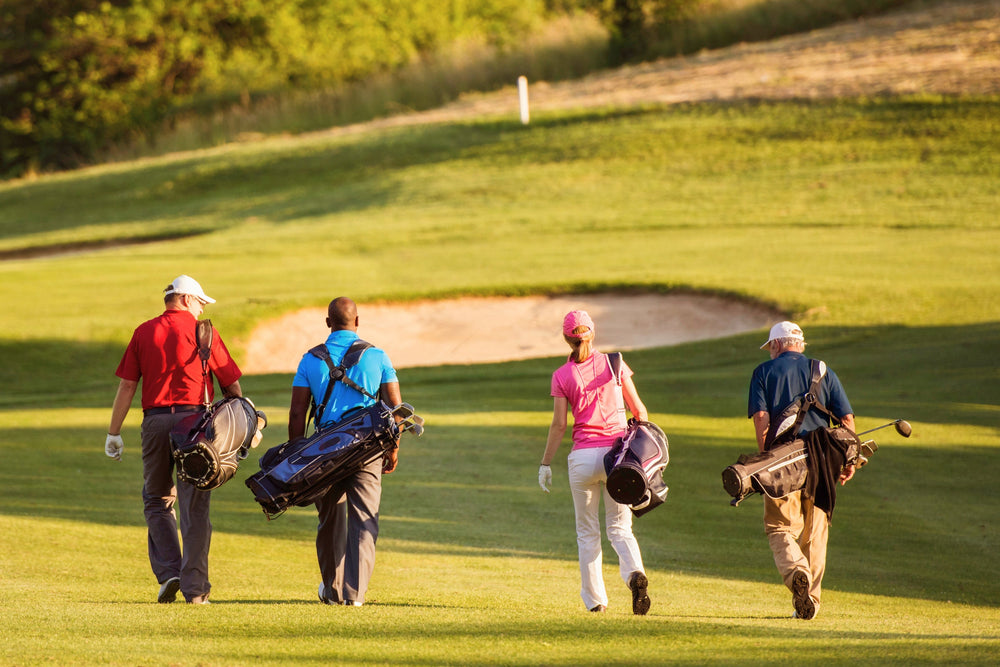 group of golfers carrying stand bags toward sand bunker on greens